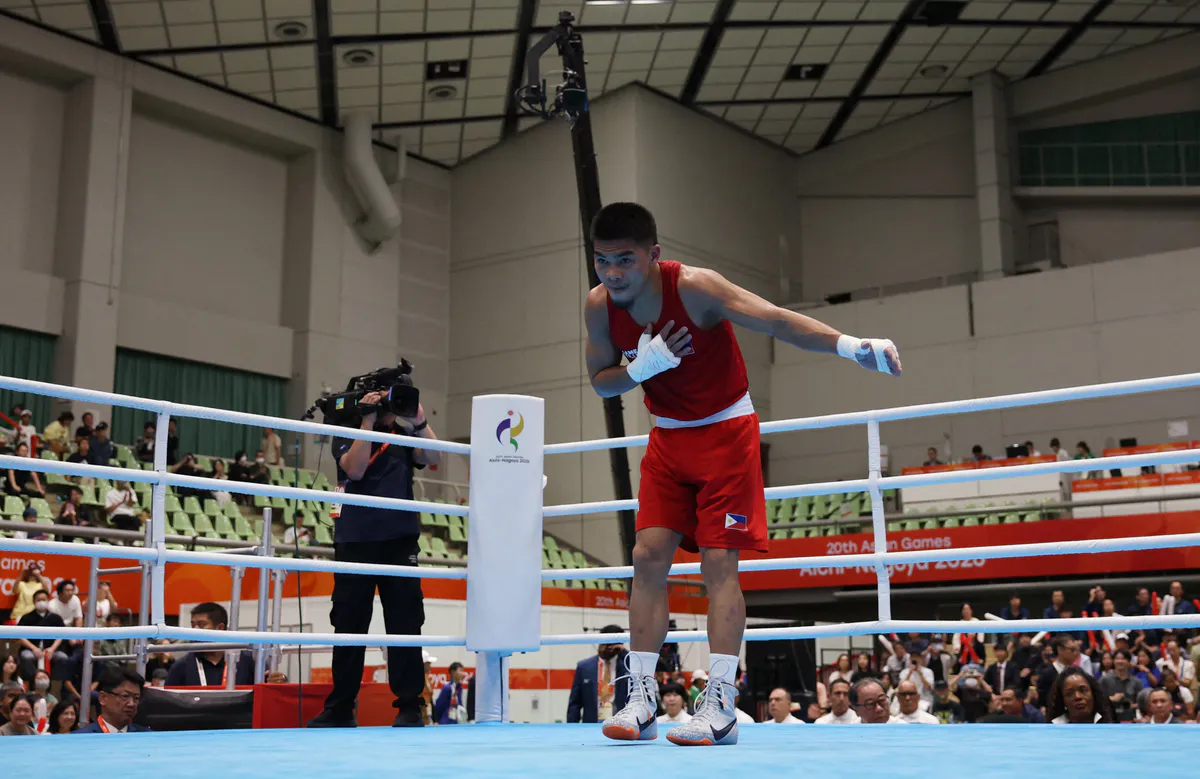 Boxing gloves beside the ropes of a boxing ring