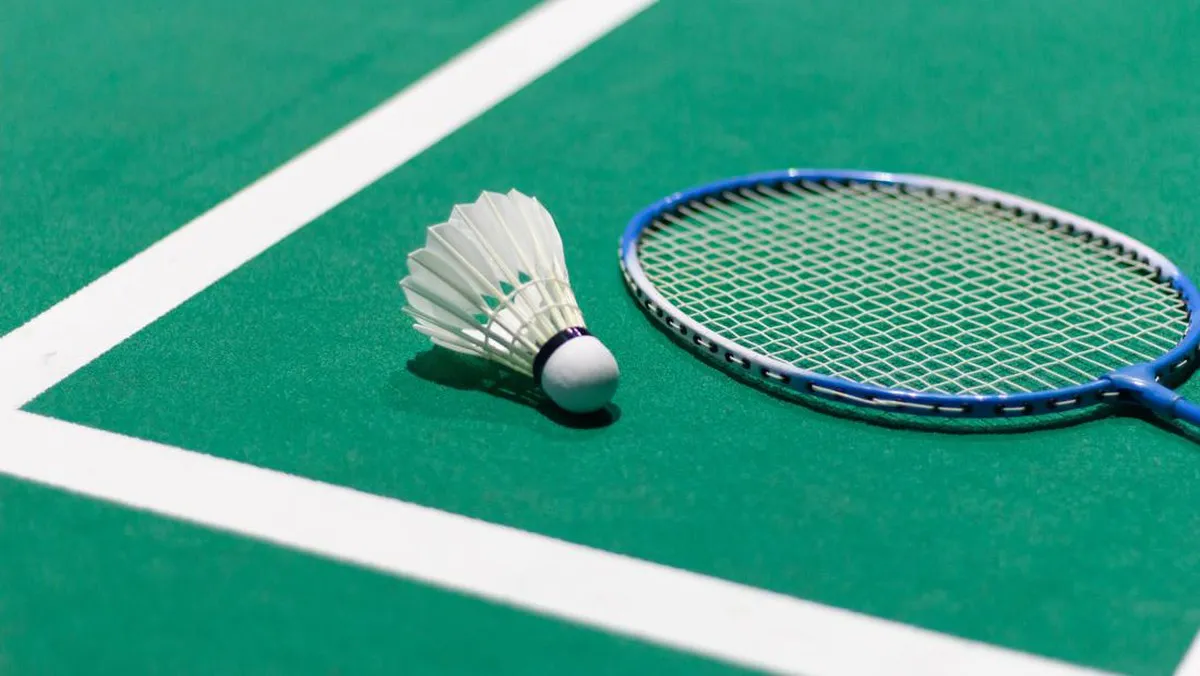 Shuttlecock and badminton rackets beside an indoor court