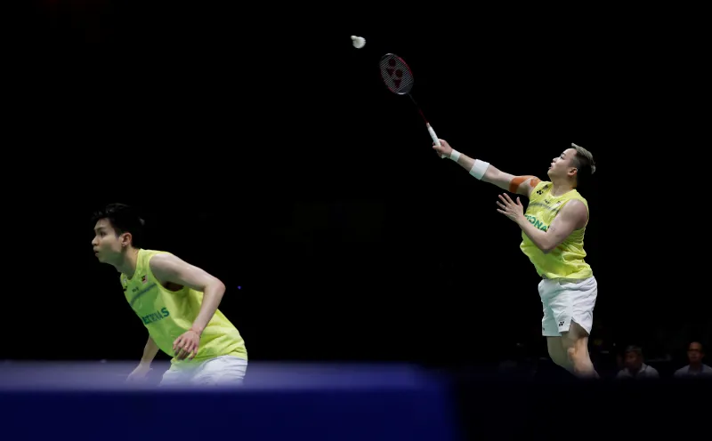 Badminton rackets and a shuttlecock beside an indoor court