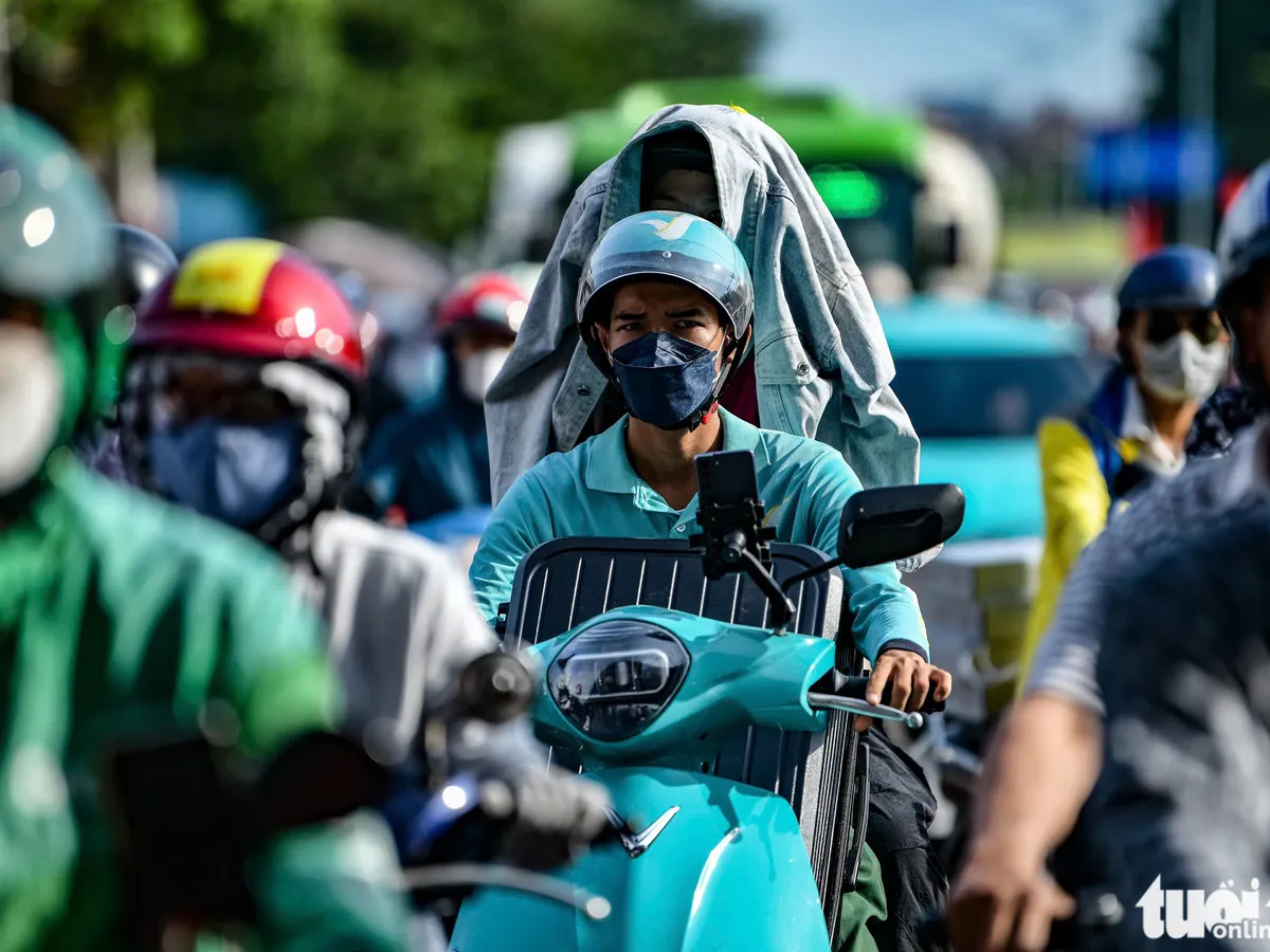 Motorbikes and cars travelling along an urban road in Vietnam