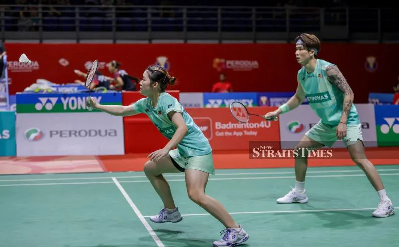 Badminton rackets and a shuttlecock beside a court