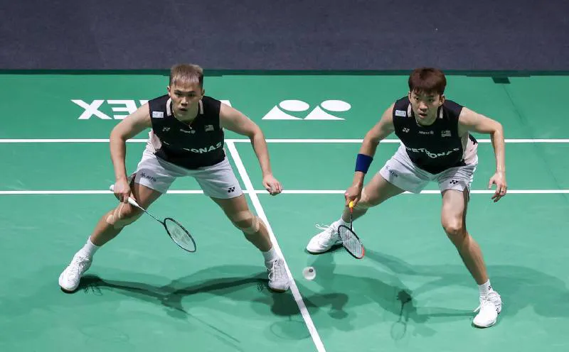 Shuttlecock and rackets beside a badminton court