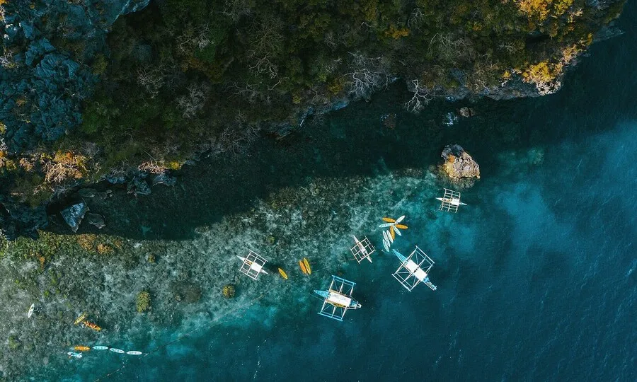 Dive boats beside a forested coastline in the Philippines