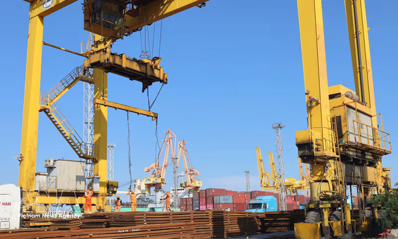 Cargo barge travelling along a waterway near container port facilities
