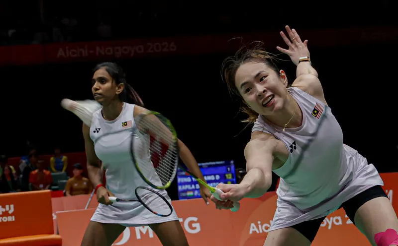 Badminton rackets and a shuttlecock beside an indoor court