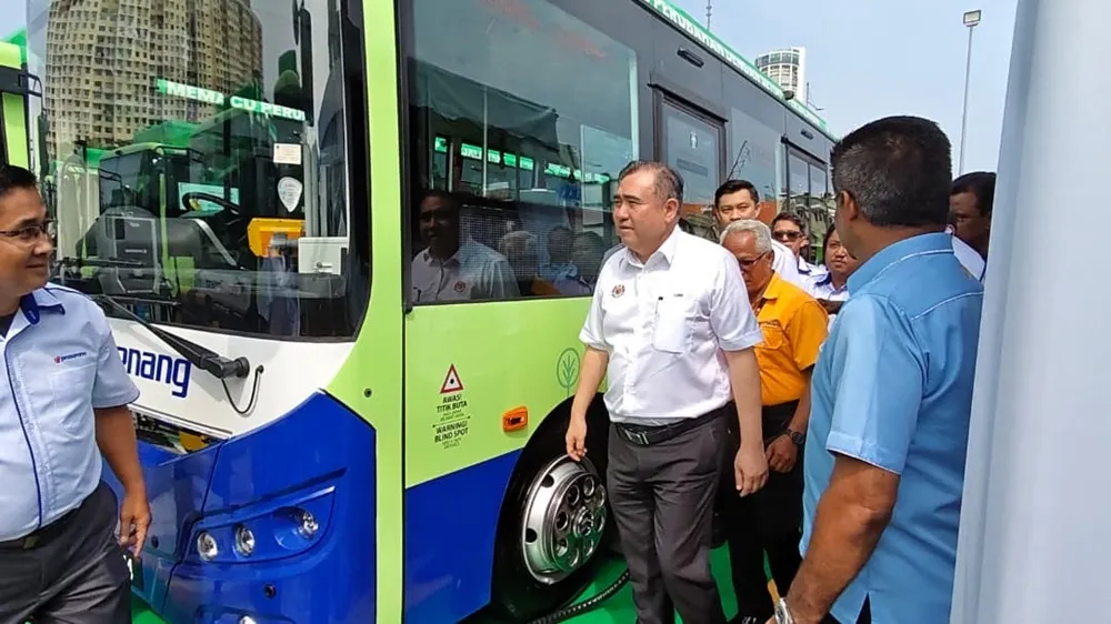 Electric buses parked beside charging equipment at a bus depot