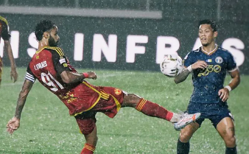 Football on a rain-soaked pitch under stadium floodlights