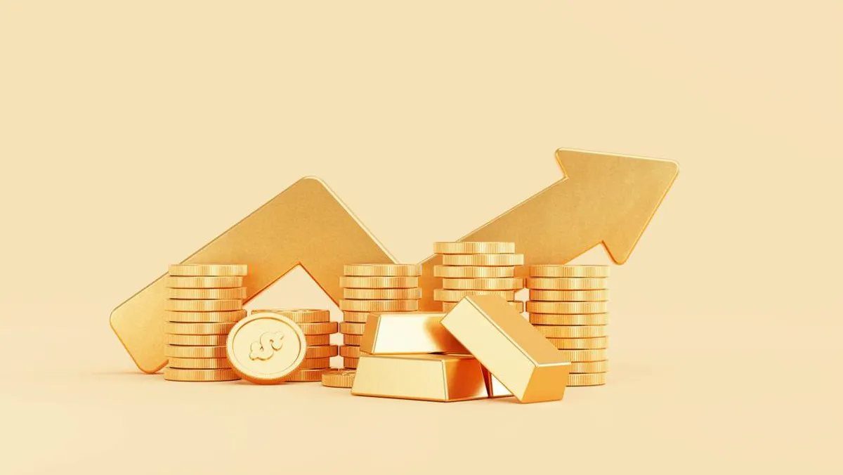 Gold bars beside a smartphone displaying a financial chart