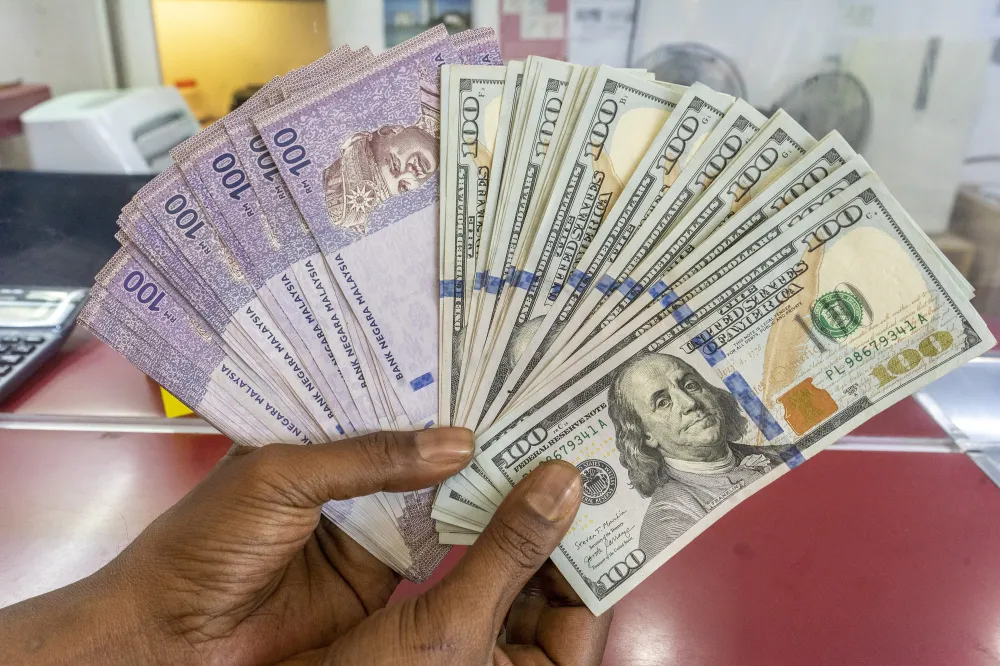 Malaysian ringgit banknotes beside US dollar notes