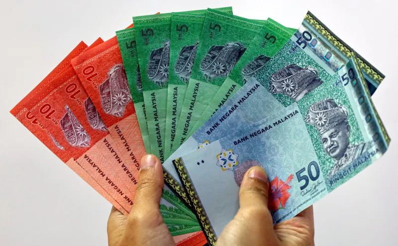 Malaysian ringgit banknotes beside US dollar banknotes