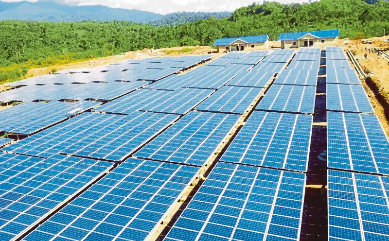 Solar panels with electricity transmission towers in the background