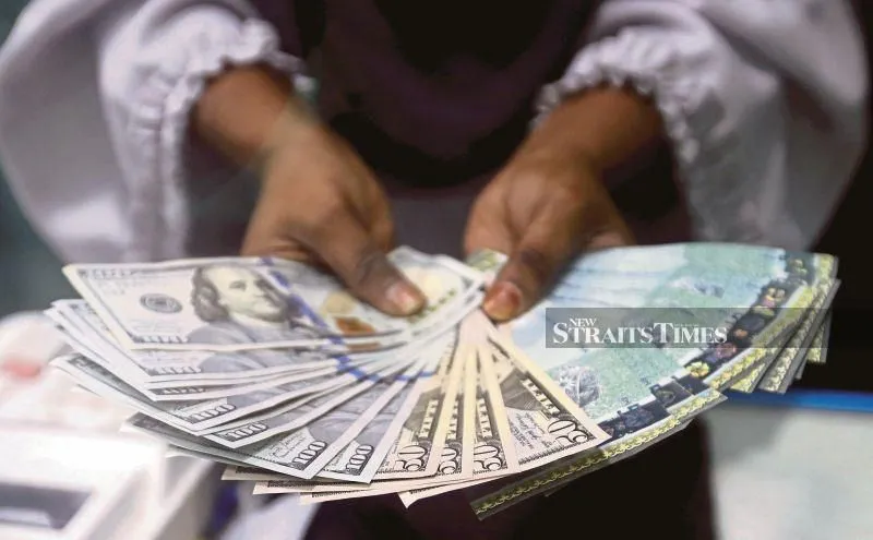 Malaysian ringgit banknotes beside US dollar notes