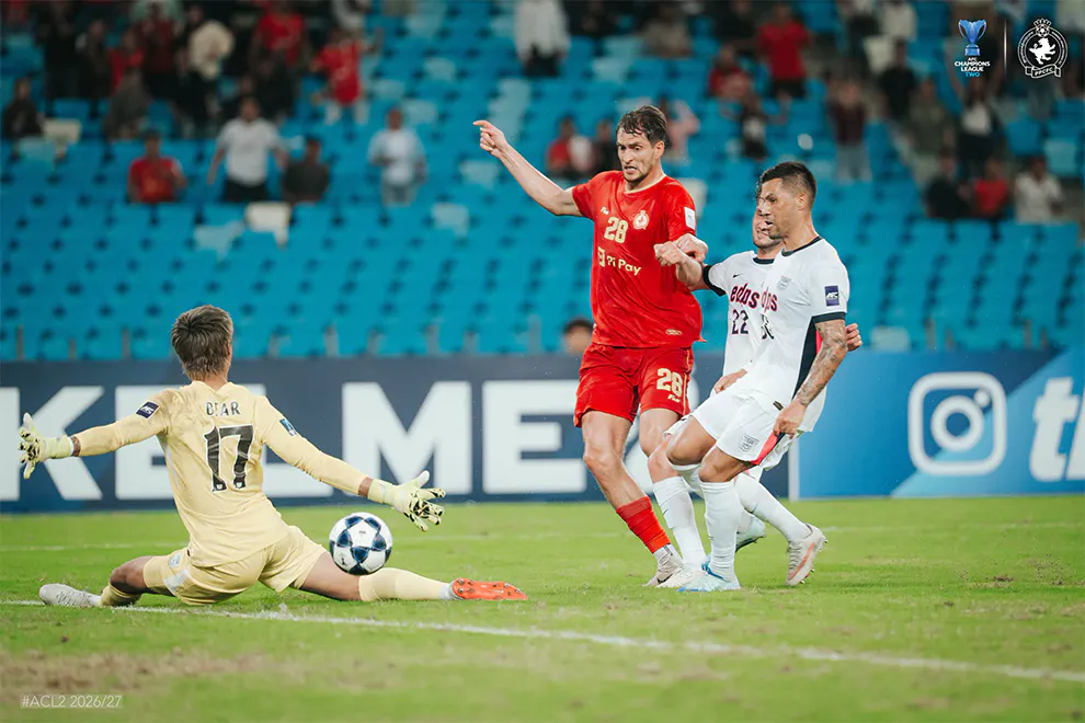 Football on a pitch under stadium floodlights
